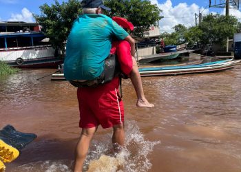 Bombeiro carrega idoso nas costas durante resgate em área alagada no Rio Juruá