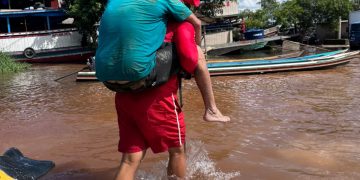 Bombeiro carrega idoso nas costas durante resgate em área alagada no Rio Juruá